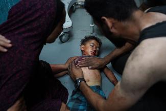 La mère d’un enfant palestinien tient son épaule alors qu'un homme essaie de le sauver à l'hôpital des Martyrs d'Al-Aqsa dans le centre de la bande de Gaza. © Bashar Taled / AFP